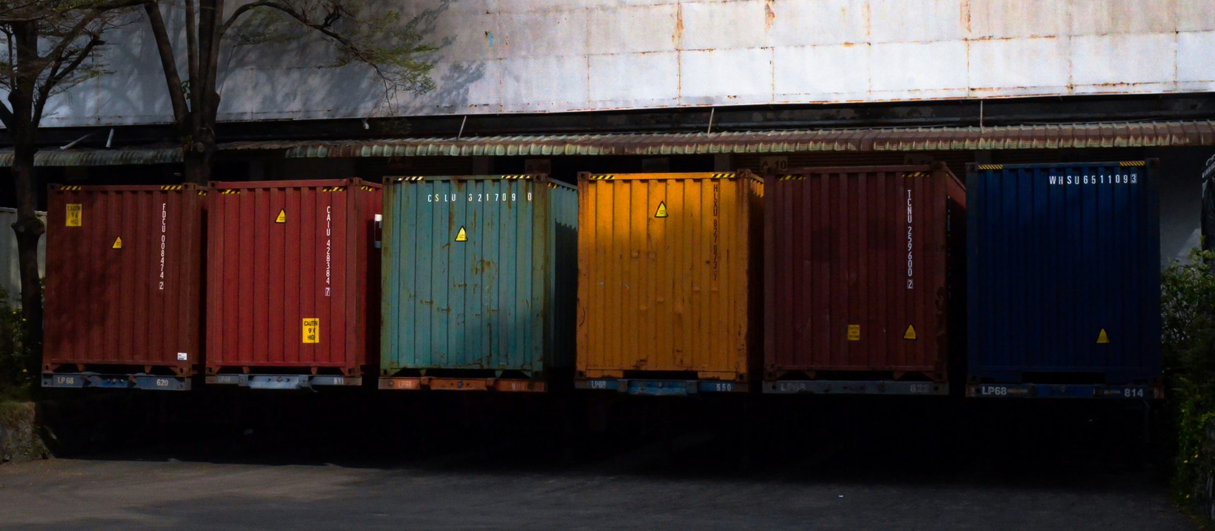 A row of weathered shipping containers in primary colours