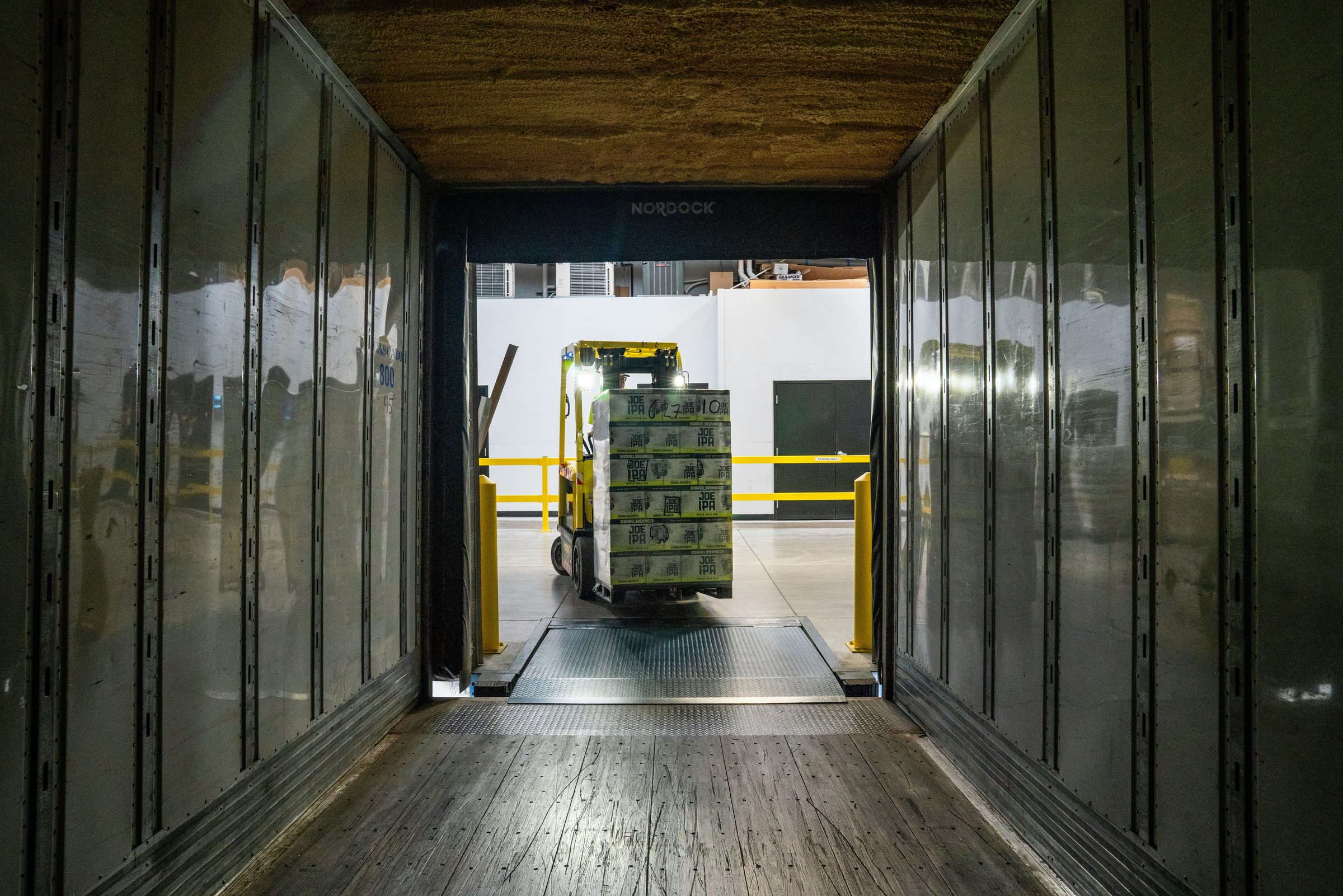 Forklift loading palletised cargo into a refrigerated trailer at the dock
